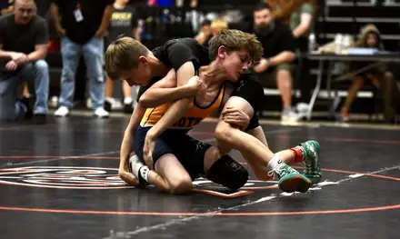 Two young wrestlers scramble on the mat at a tournament