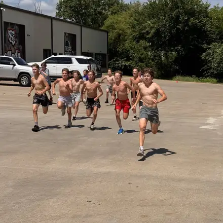 AWC athletes sprinting through an outdoor conditioning run in the parking lot.