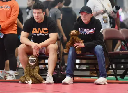 Two AWC coaches watching a match from the corner chairs, team mascots beside them