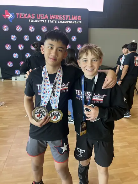 Two AWC teammates with their medals at the Texas USA Wrestling backdrop