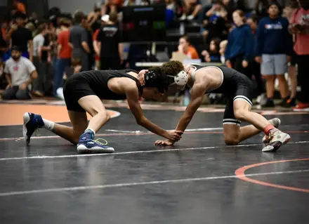 Two AWC wrestlers scramble for the takedown in front of a full crowd