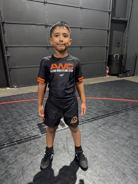 A young AWC wrestler in club gear standing on the mat before a session
