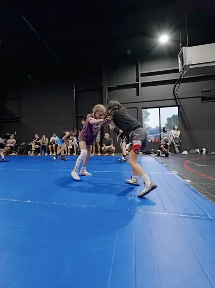 Young wrestlers carrying partners across the mat during warm-ups.