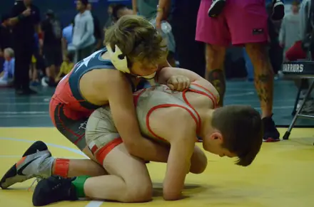 A wrestler works from the top position during a tournament bout