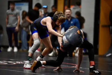An AWC wrestler drives an opponent backwards during a match
