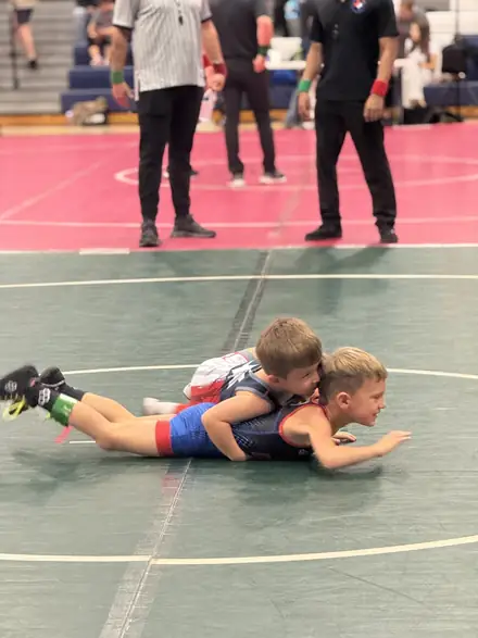 Two young wrestlers competing on the mat at a youth tournament