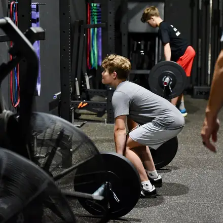 An athlete cleaning a loaded barbell during a strength session.