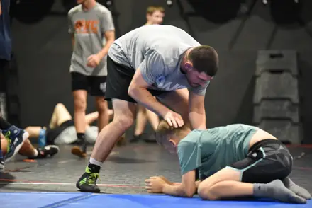 A coach demonstrating a technique on the mat during a club practice