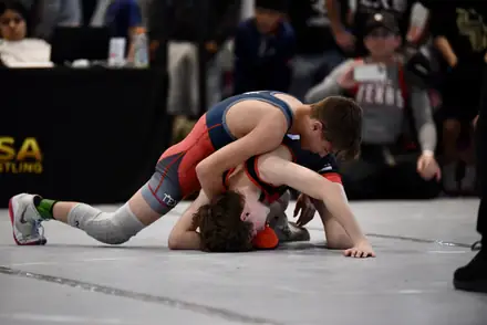 A wrestler lifts an opponent off the mat during a tournament match