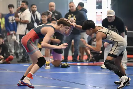 Two wrestlers hand fight from a neutral stance at a tournament