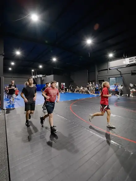 Wrestlers jogging warm-up laps around the edge of the mat.